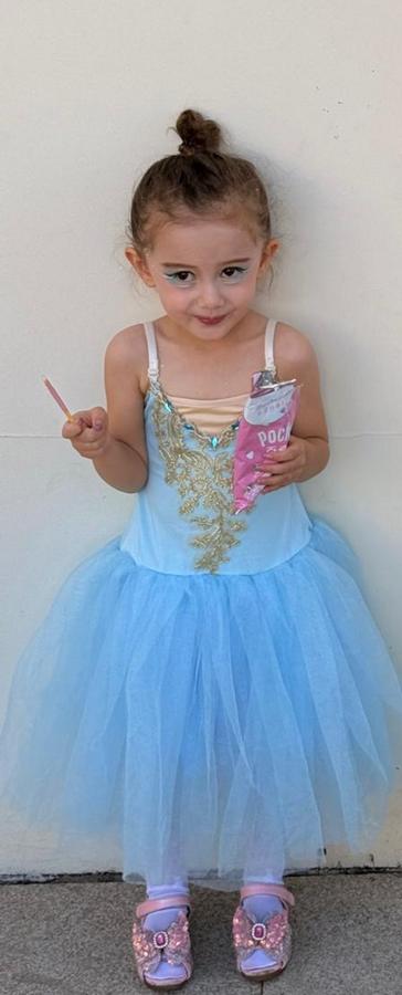 Leonie in a blue ice-princess dress holding a pink snack pouch